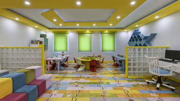 Una sala de juegos infantil con muebles coloridos, una mesa de juegos y juguetes educativos.