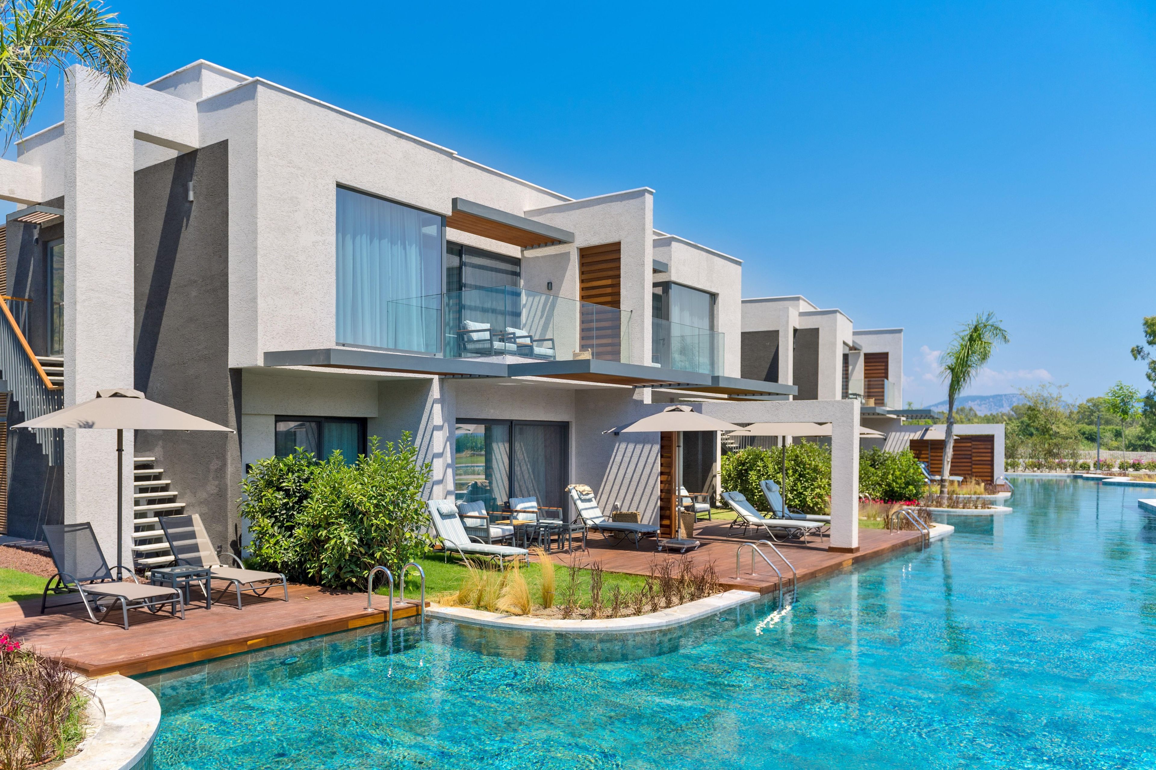 A modern hotel with a pool, multiple balconies, and outdoor seating areas.