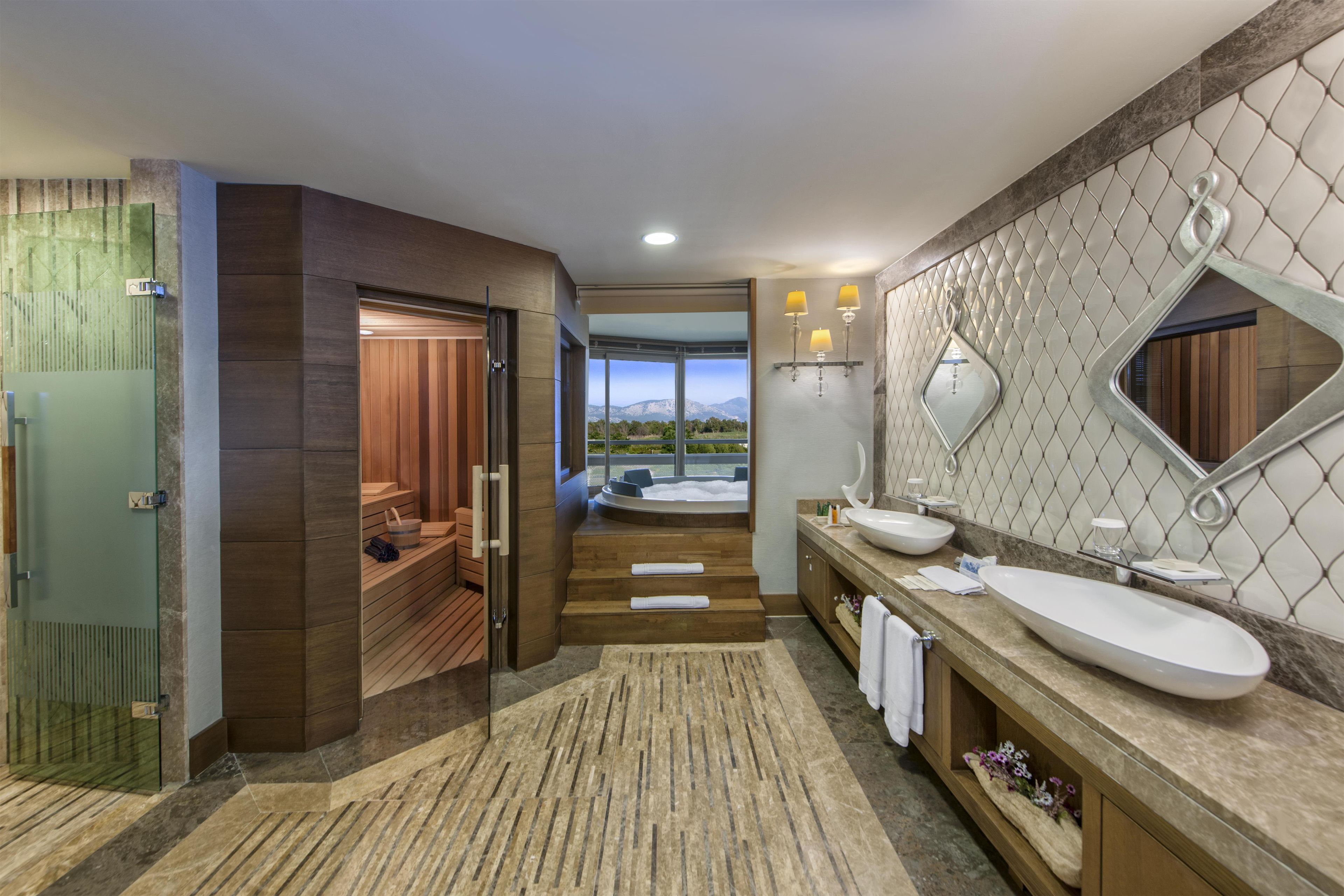 A modern bathroom with a large mirror, two sinks, and a sauna.