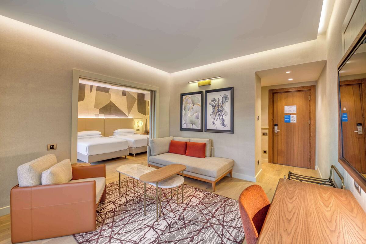 Een moderne hotelkamer met een bed, een bank, een fauteuil en een kleine tafel.