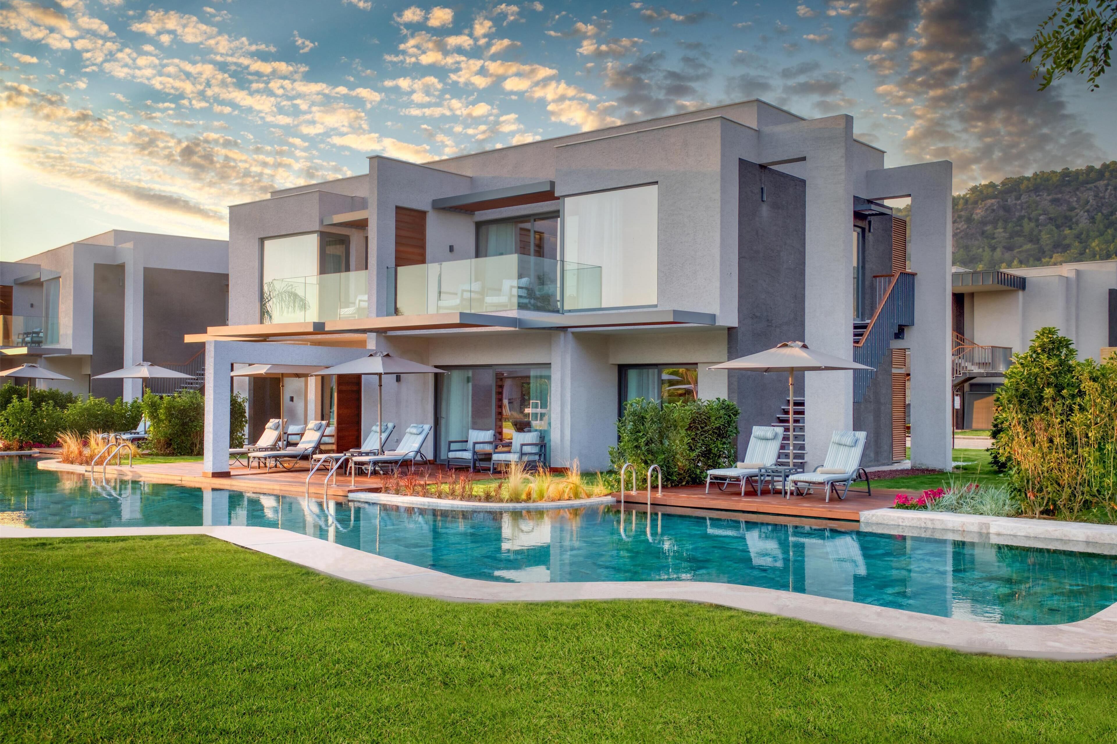 A modern multi-story house with a swimming pool, outdoor seating, and a staircase.