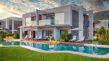 A modern multi-story house with a swimming pool, outdoor seating, and a staircase.