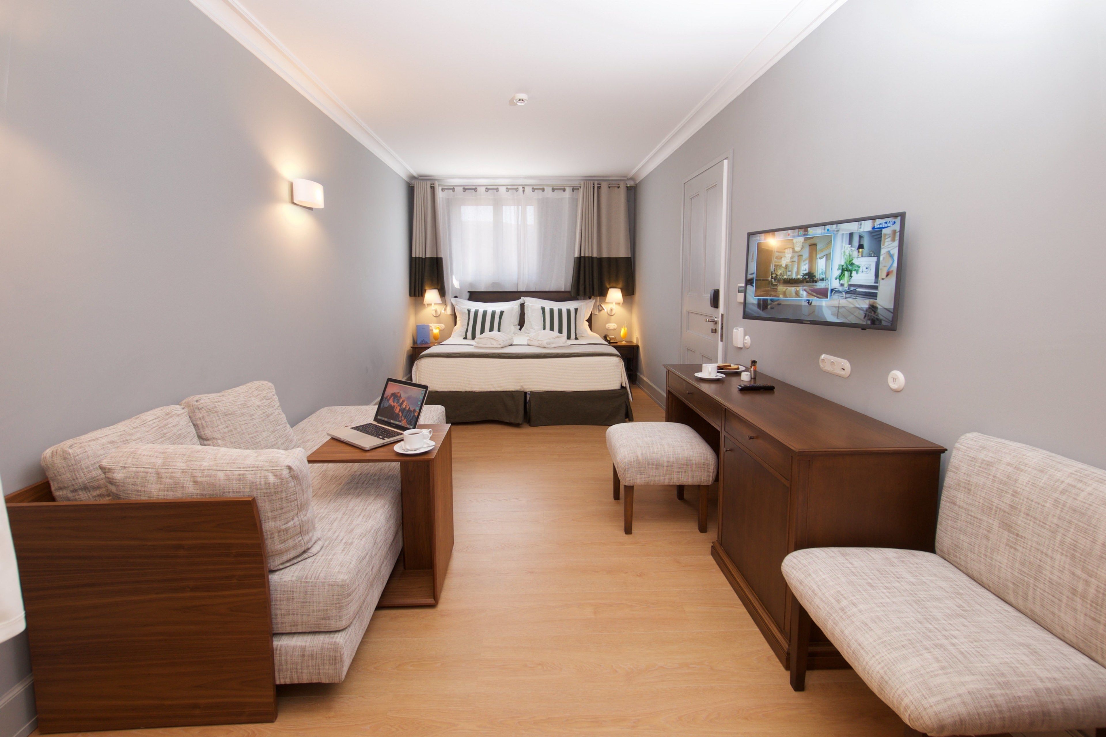 Una habitación de hotel con una cama, dos sofás, un escritorio y una televisión.