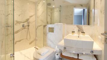A modern bathroom with a glass-enclosed shower, a white toilet, and a double sink vanity with a mirror.