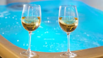 Two glasses of white wine on a golden surface with a blue pool in the background.