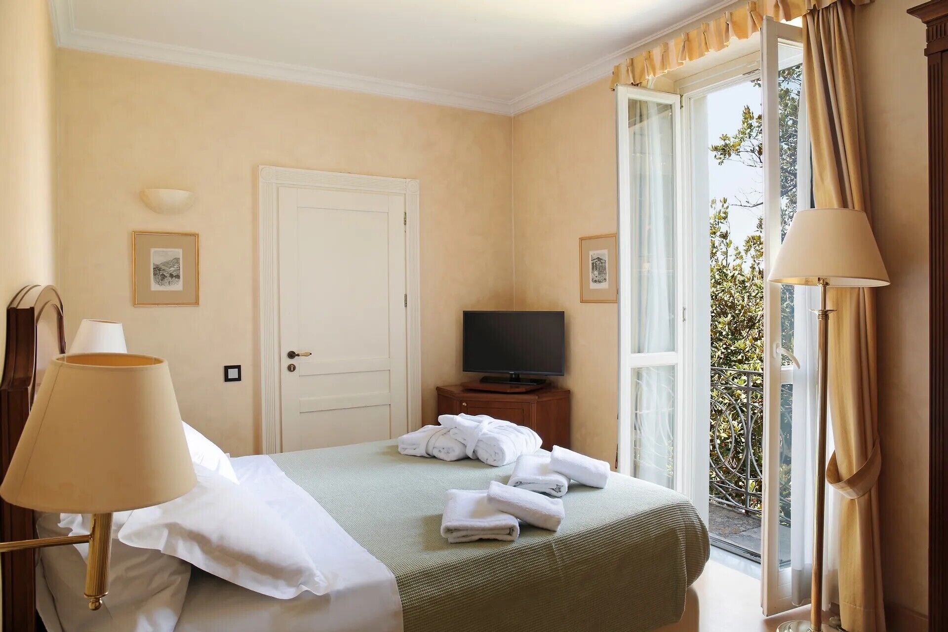 A hotel room with a bed, a television, a door, and a window with curtains.