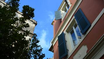 Un edificio con fachada roja, contraventanas azules y cielo azul despejado.