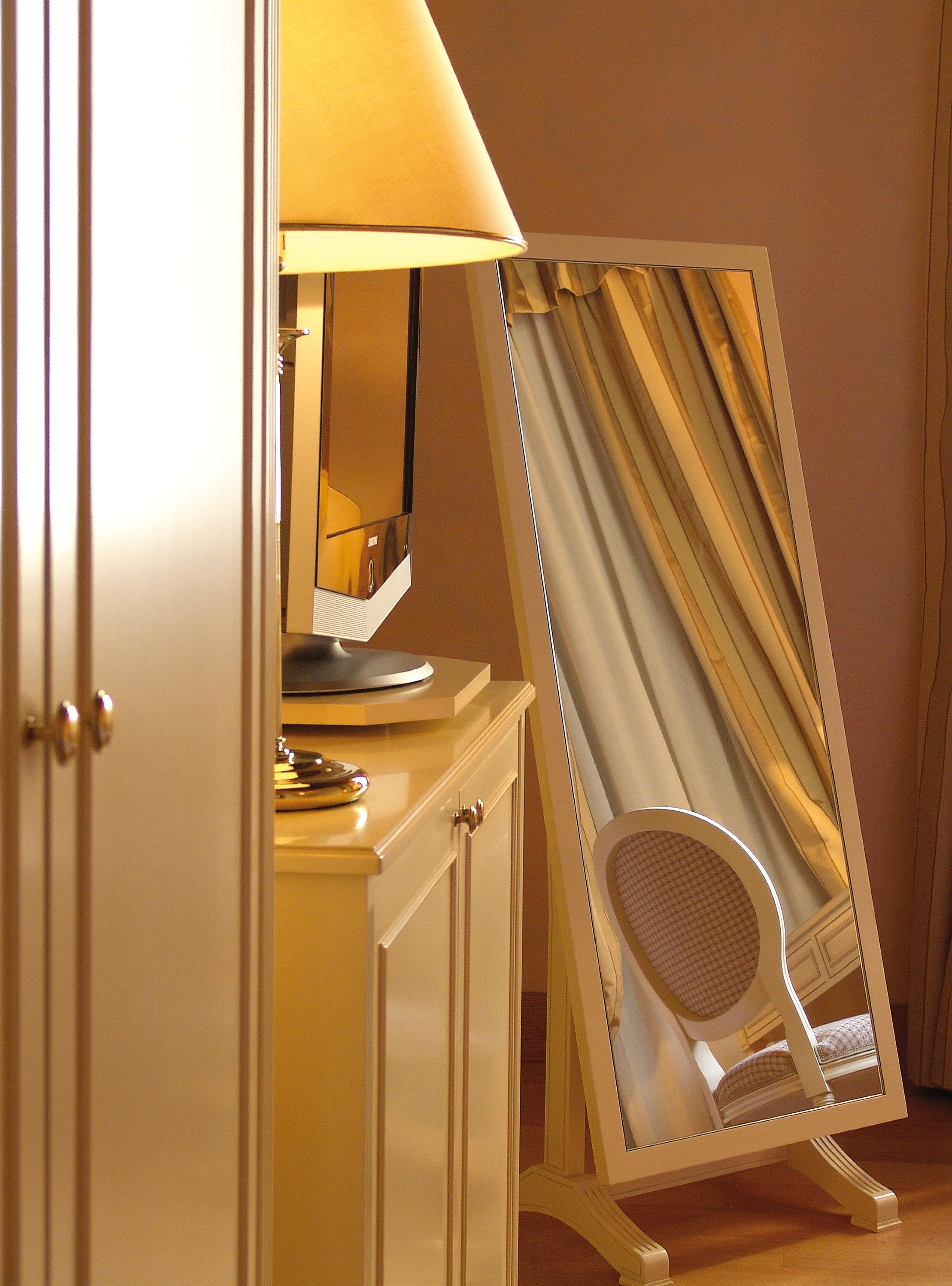 A room with a mirror, a lamp, and a chair.