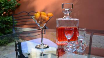 Een glazen tafel met een martini-glas, een decanter en twee wijnglazen gevuld met rode vloeistof.