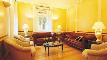 A living room with a brown leather sofa, two armchairs, a coffee table, and two lamps.