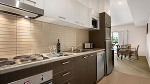 Una cocina moderna con electrodomésticos de acero inoxidable, horno empotrado y comedor con mesa y sillas.