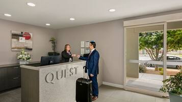 A reception desk labeled "QUEST" with a receptionist and a guest.
