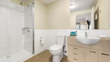Ein modernes Badezimmer mit Duschkabine aus Glas, Toilette in Weiß und Beige Waschtisch mit Spüle und Spiegel.