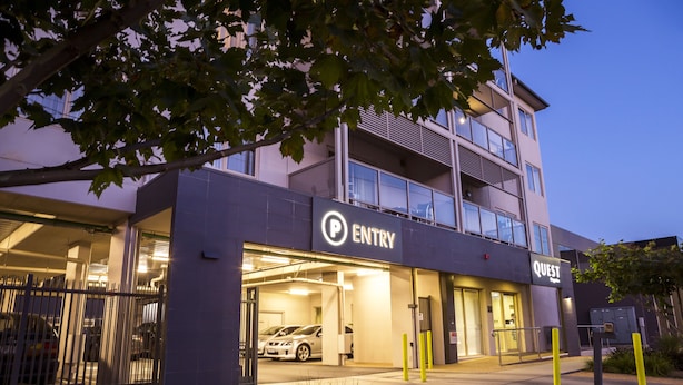 Un edificio moderno con la entrada de un estacionamiento señalada con los rótulos "ENTRY" y "QUEST".