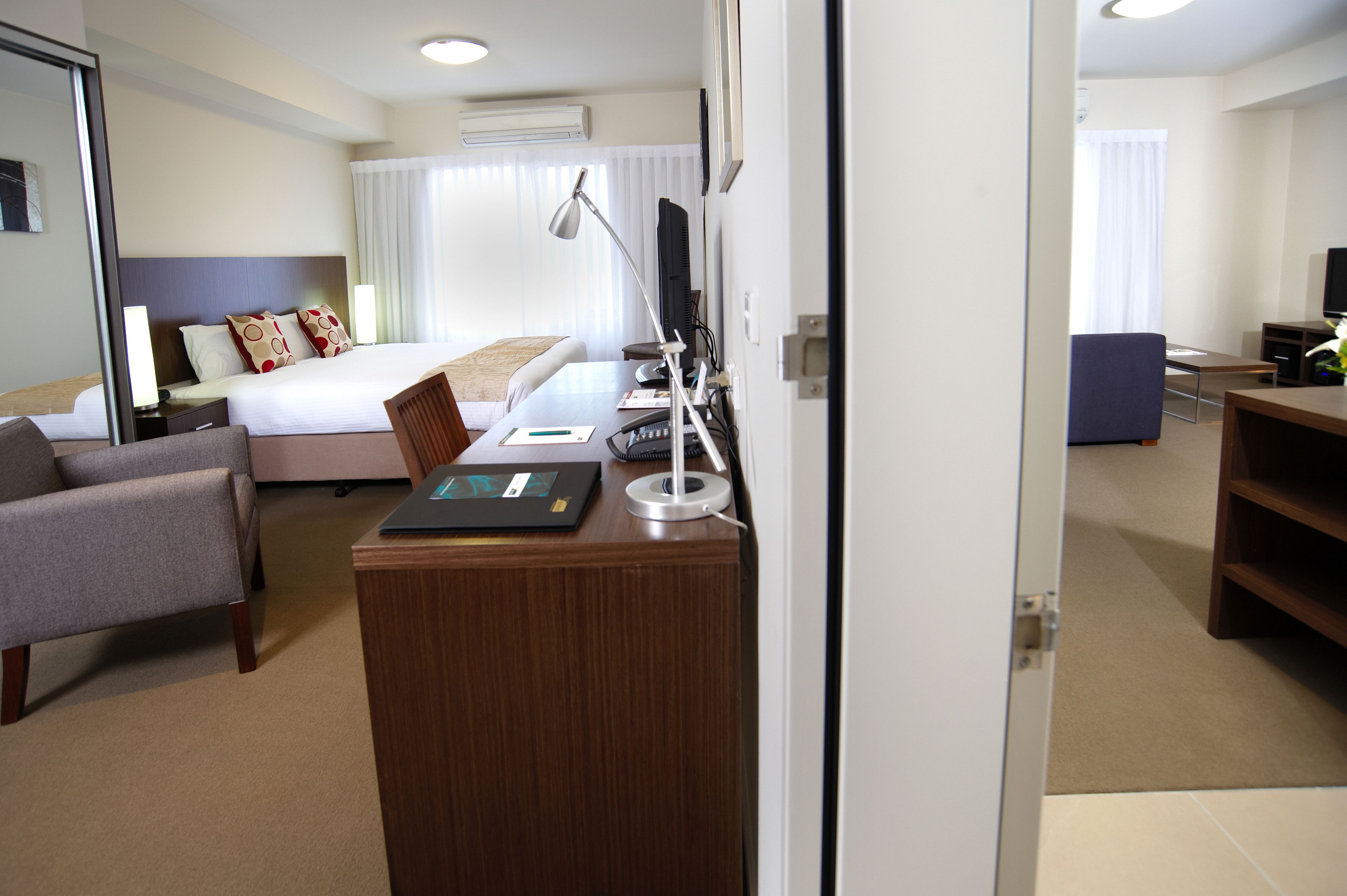 A hotel room with a bed, a desk with a computer, a chair, and a TV.