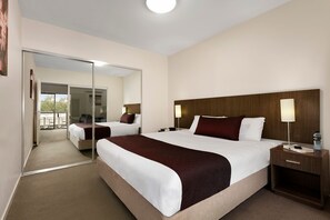 A hotel room with a large bed, a nightstand, a mirror, and a view of the outside balcony.