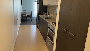 Una cocina moderna con electrodomésticos de acero inoxidable, un comedor con mesa y sillas, y vistas al salón.