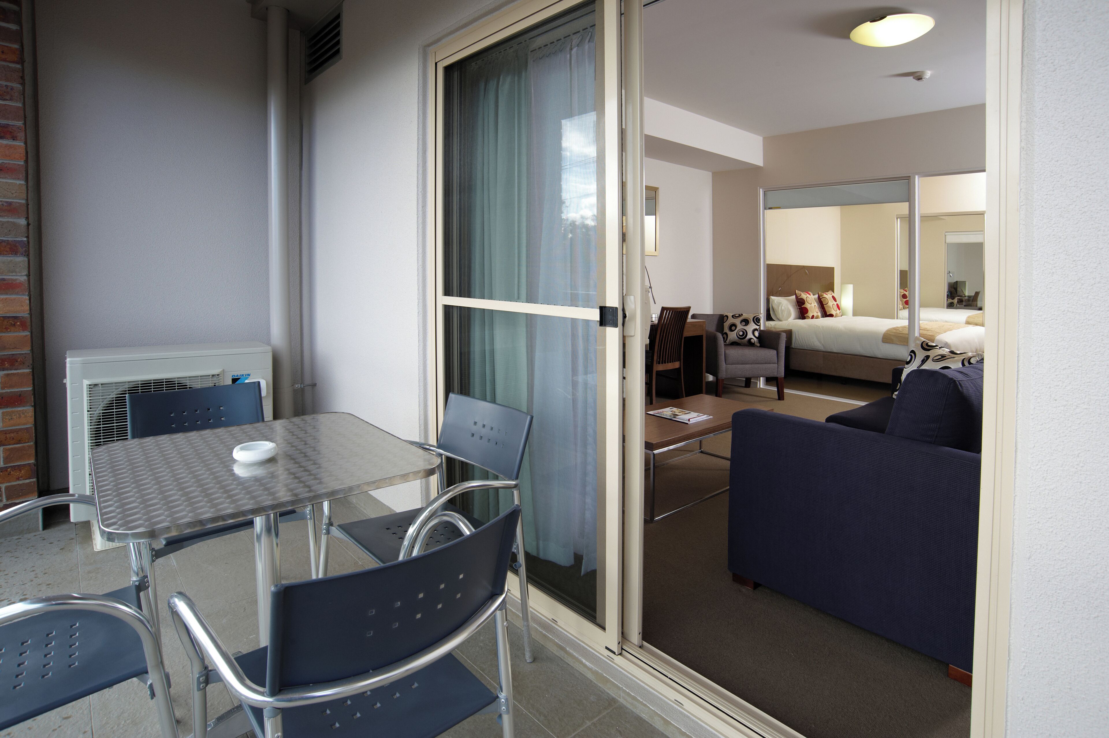 Ein Hotelzimmer mit Glastür zu einem Balkon, einem Bett, einem Sofa, einem Tisch und Stühlen.
