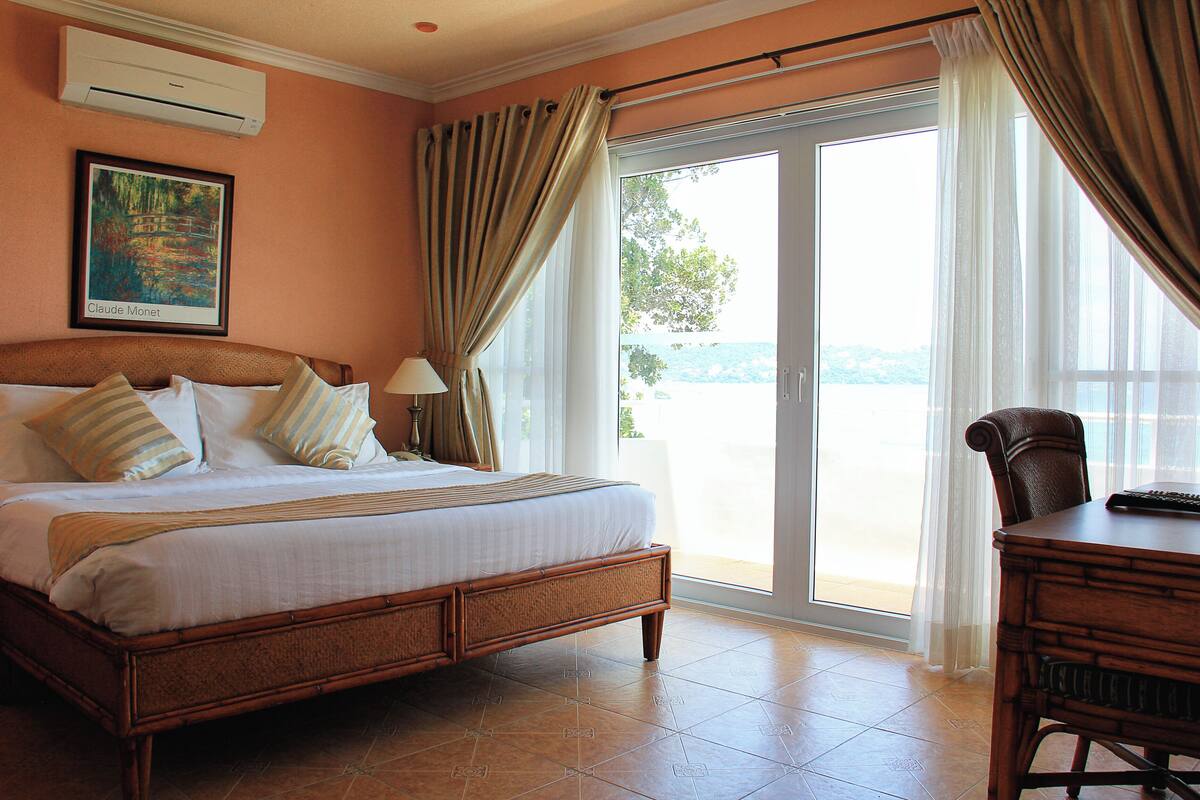 Habitación de hotel con una cama grande, un escritorio y vistas al exterior.