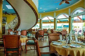 A restaurant with multiple tables set for dining, featuring wooden chairs and a ceiling fan. - Breakfast At Monaco (Boracay Island)