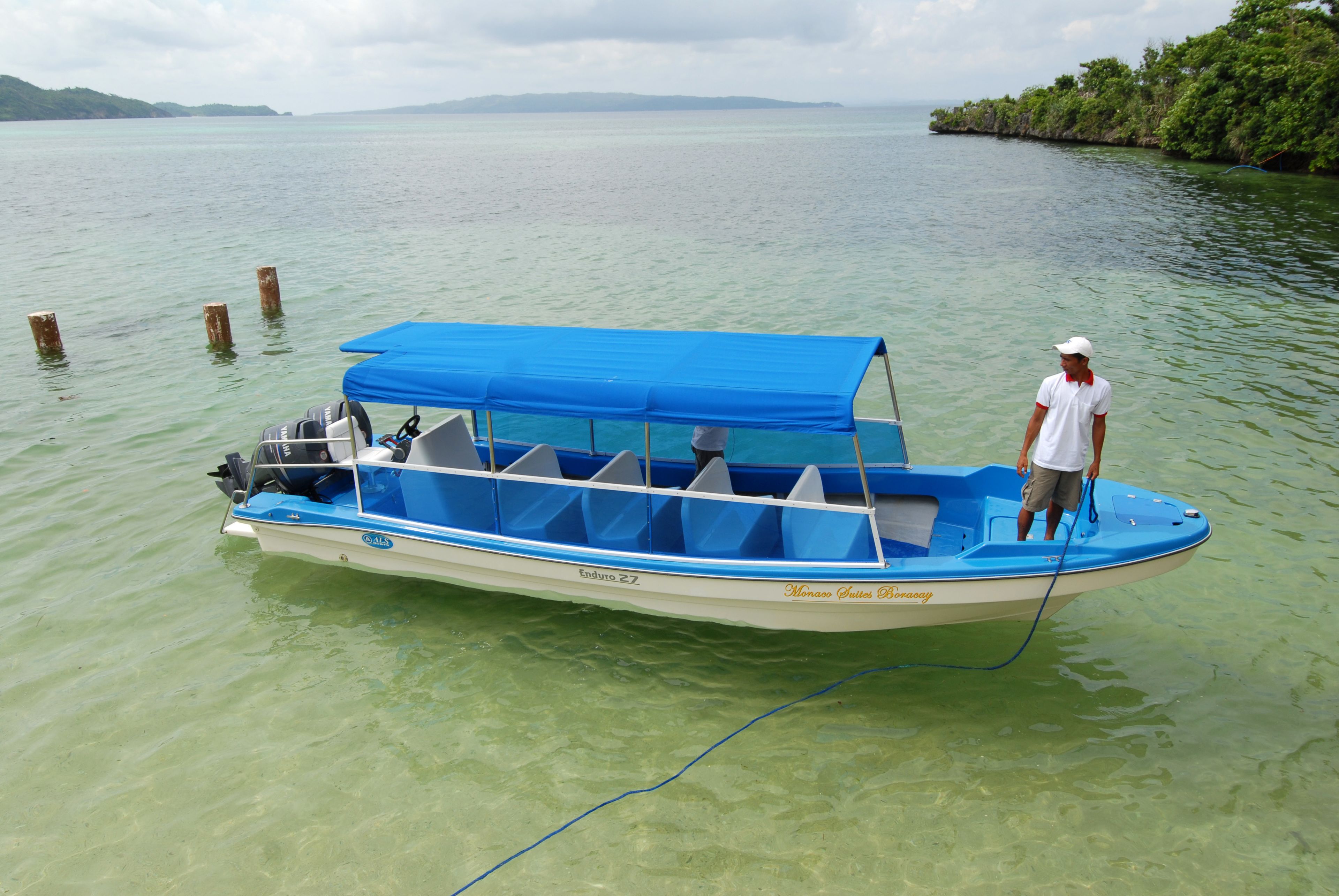 Un bateau avec un auvent bleu et une personne debout dessus.