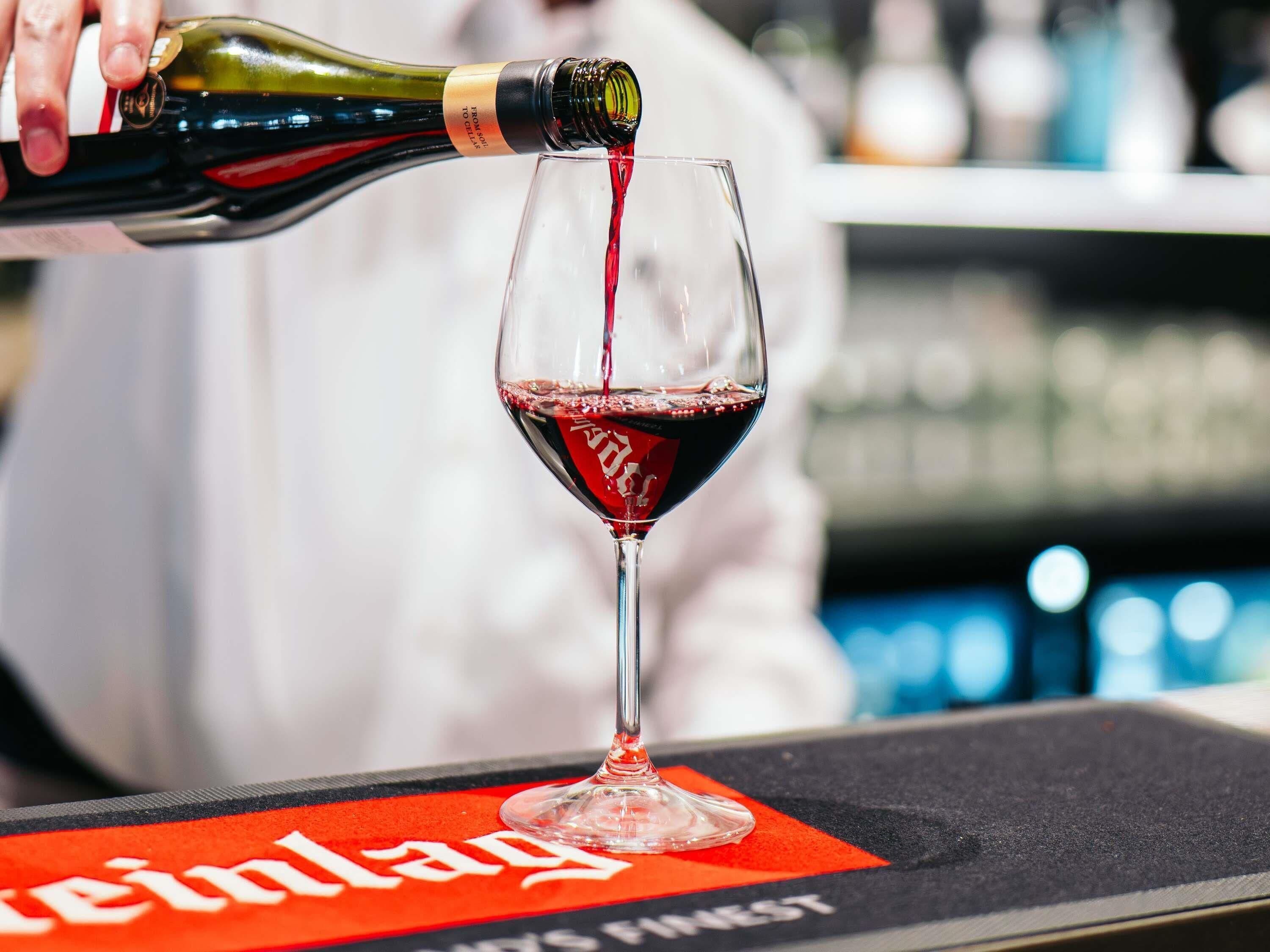A bottle of red wine being poured into a glass.