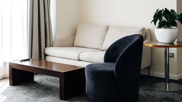 A modern living room with a sofa, a dark armchair, a coffee table, a side table with a plant, and a potted plant on the floor.