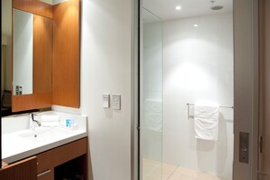Ein modernes Badezimmer mit einem Holzlager, einer Duschkabine aus Glas und einem weißen Handtuch an der Tür.