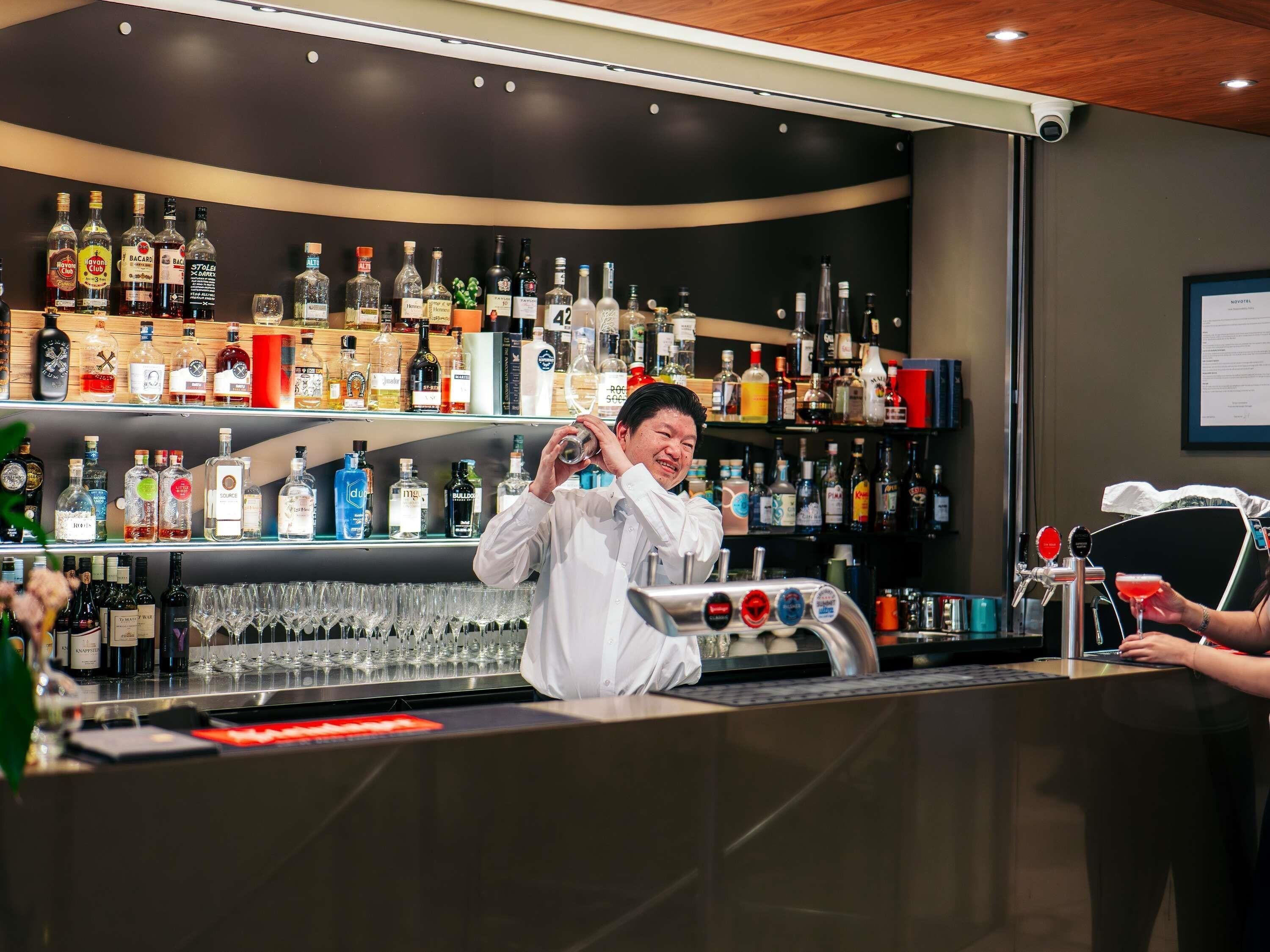 A bar area with shelves stocked with various liquor bottles and glasses.