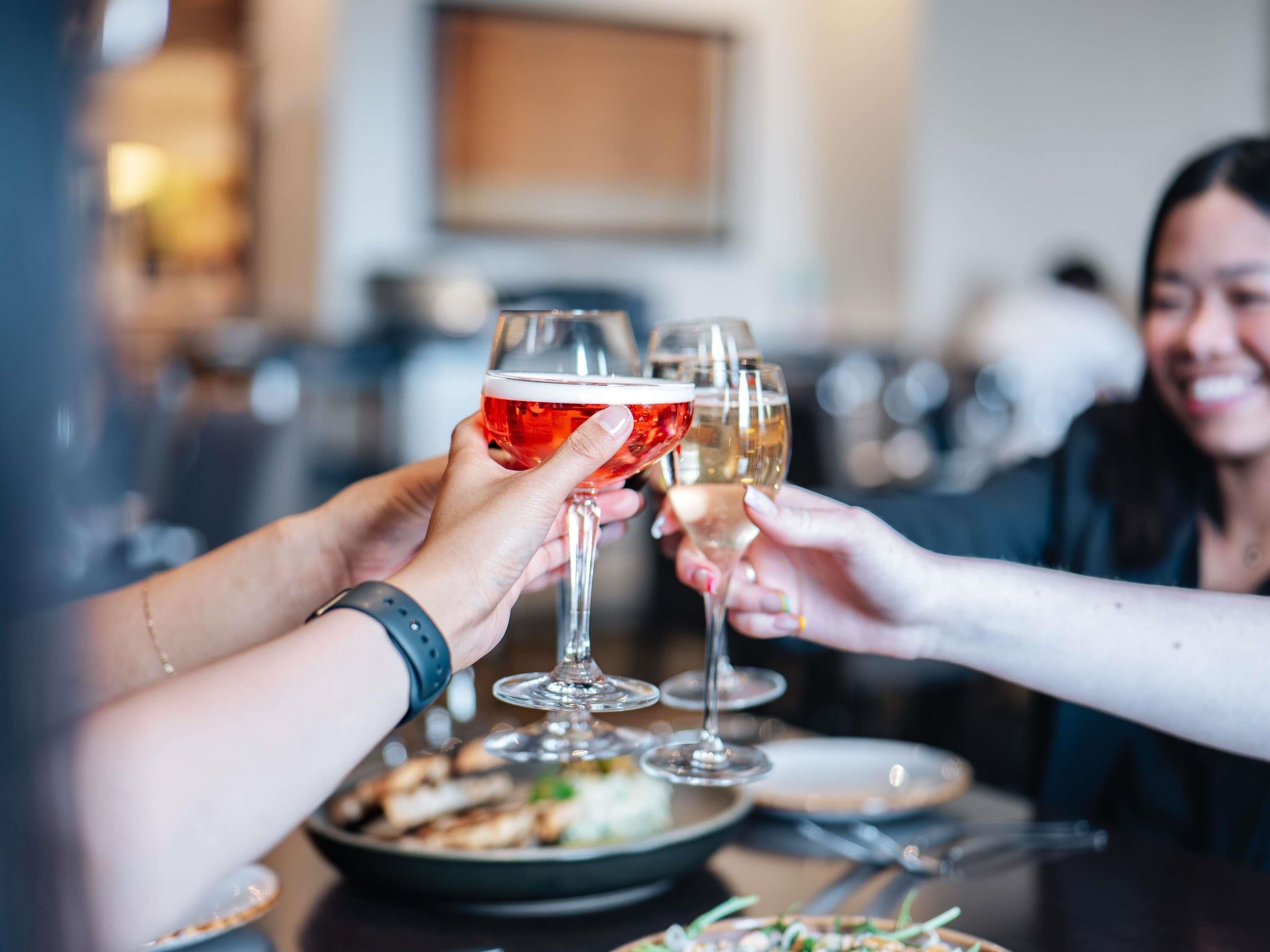 Un groupe de personnes trinquant avec des verres de vin autour d’une table dans un restaurant.