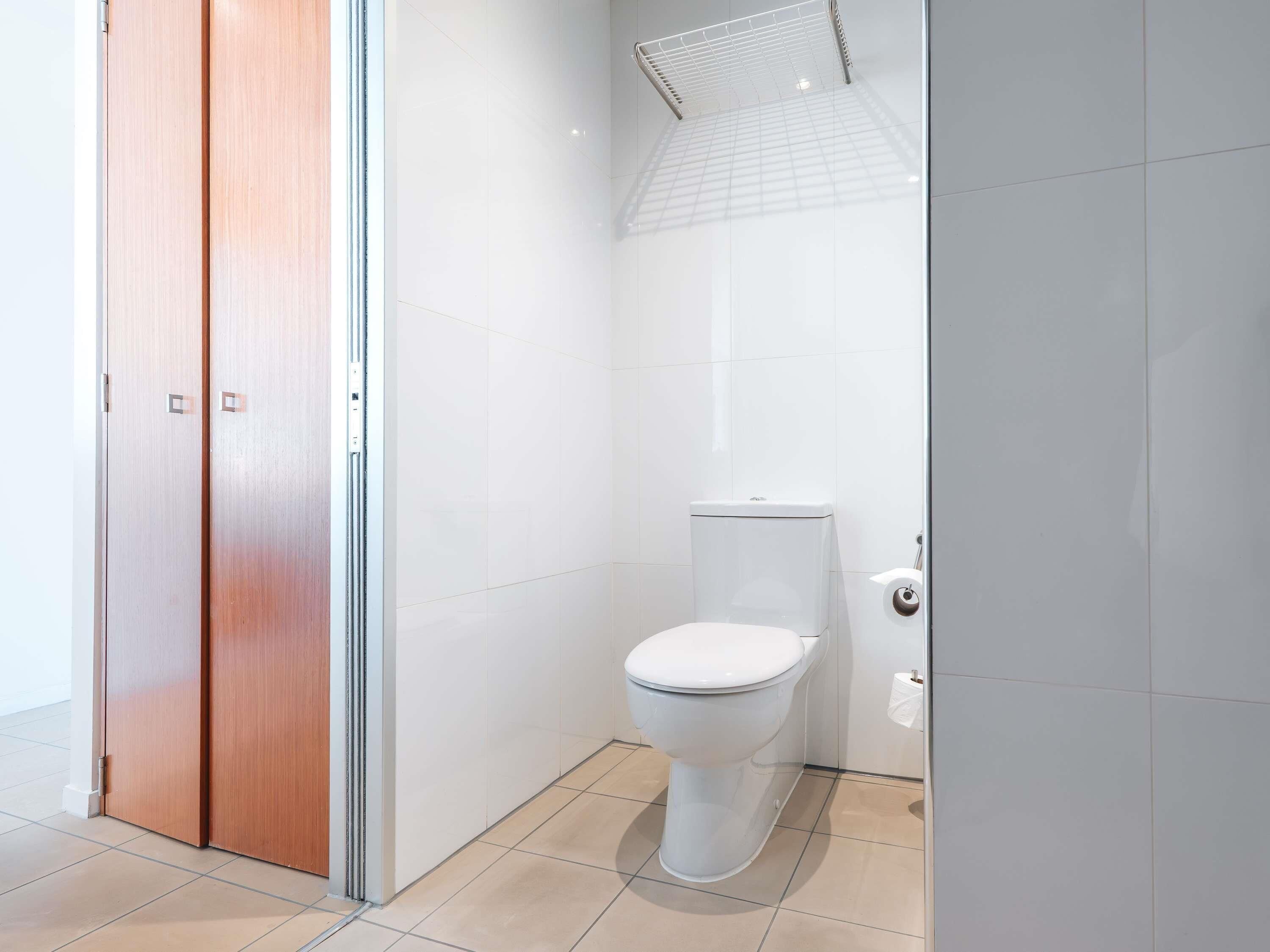 Ein modernes Badezimmer mit Toilette, Duschbereich und Holztür.