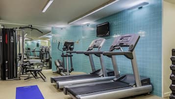 A gym with treadmills, weight machines, and a blue mat.