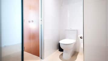 Um banheiro moderno com vaso sanitário, porta de madeira e divisória de vidro.