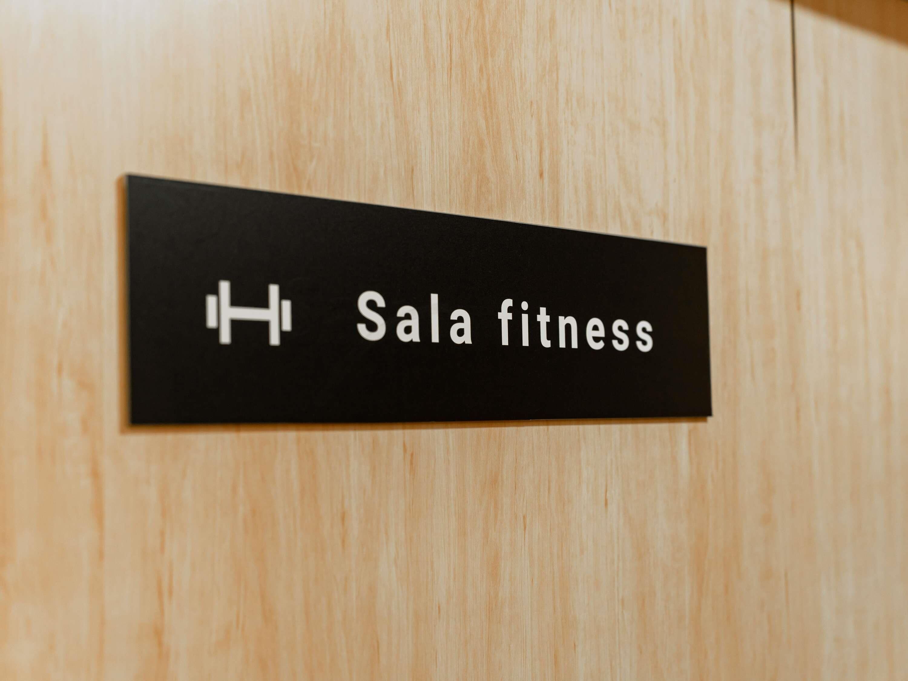 A sign on a wooden door that reads "Sala fitness".
