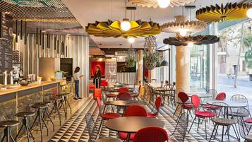 A modern cafe with a checkered floor, red and black chairs, and unique hanging light fixtures.