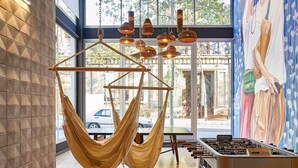 Ein Zimmer mit einer Hängematte, Lichterketten, einem Tischfußballspiel und einem Wandgemälde.