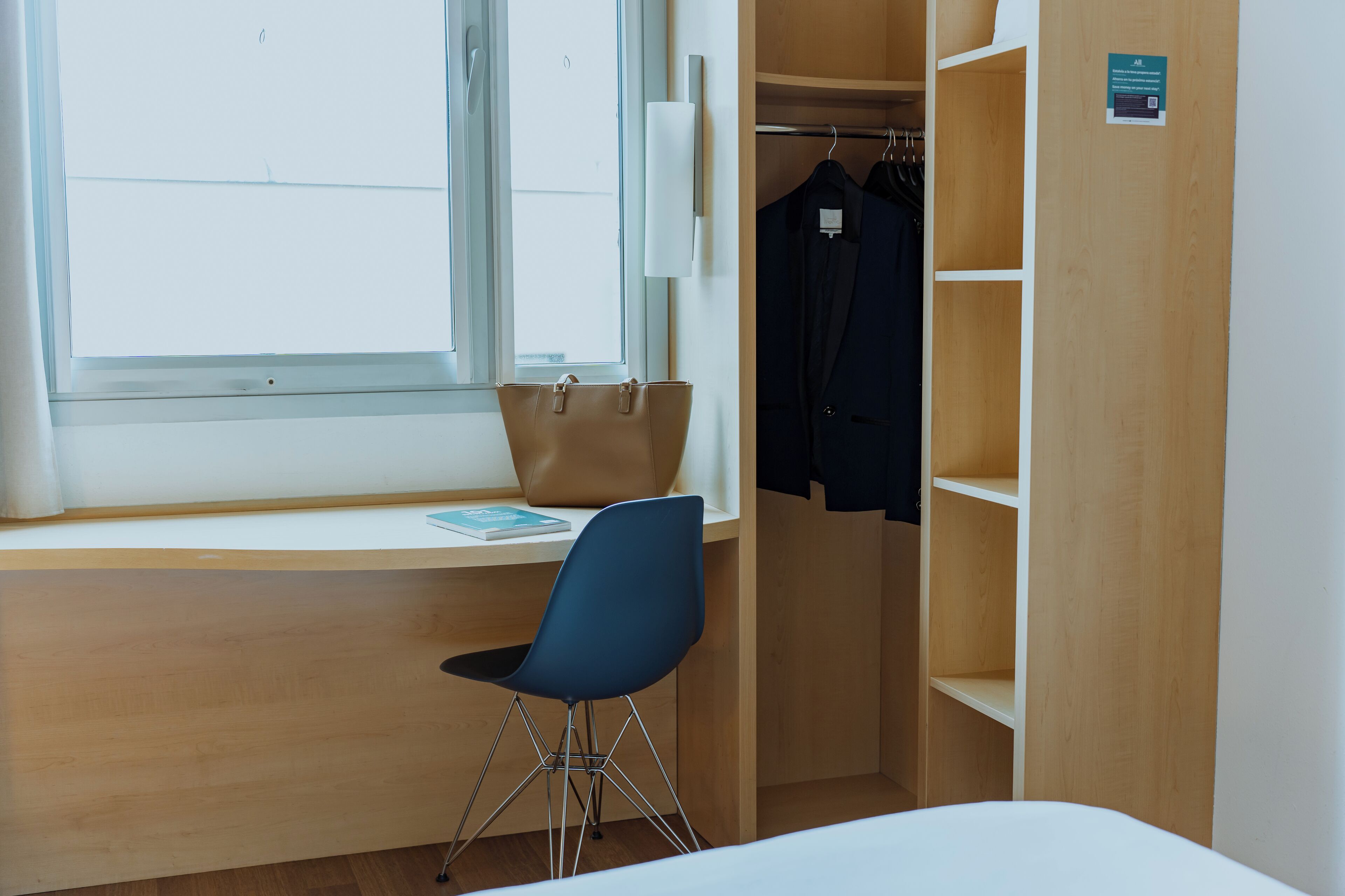 A room with a desk, a chair, a window, and a wardrobe.