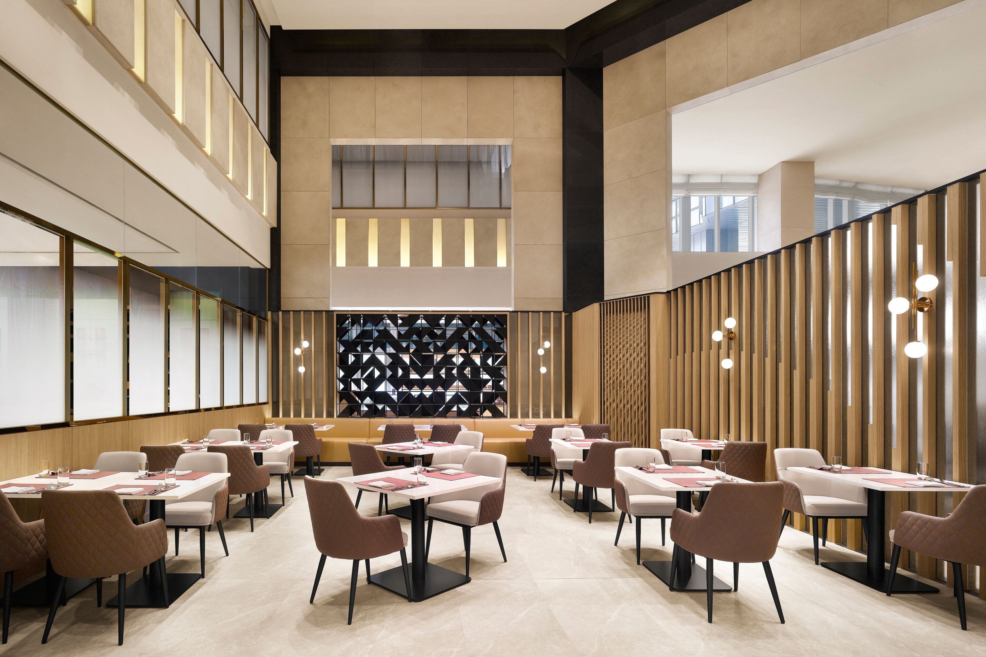 Um restaurante moderno com pé-direito alto, assentos em níveis e design de parede estampado.