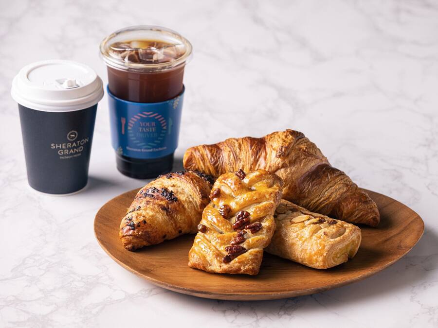 Un plato de madera con pasteles y una taza de café.
