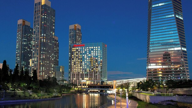 A high-rise hotel with a Marriott logo, surrounded by other tall buildings and a body of water. - Sheraton Grand Incheon Hotel (Incheon)