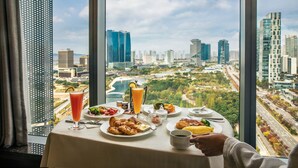 A breakfast table with various dishes, a glass of orange juice, and a view of a cityscape through large windows. - Sheraton Grand Incheon Hotel (Incheon)