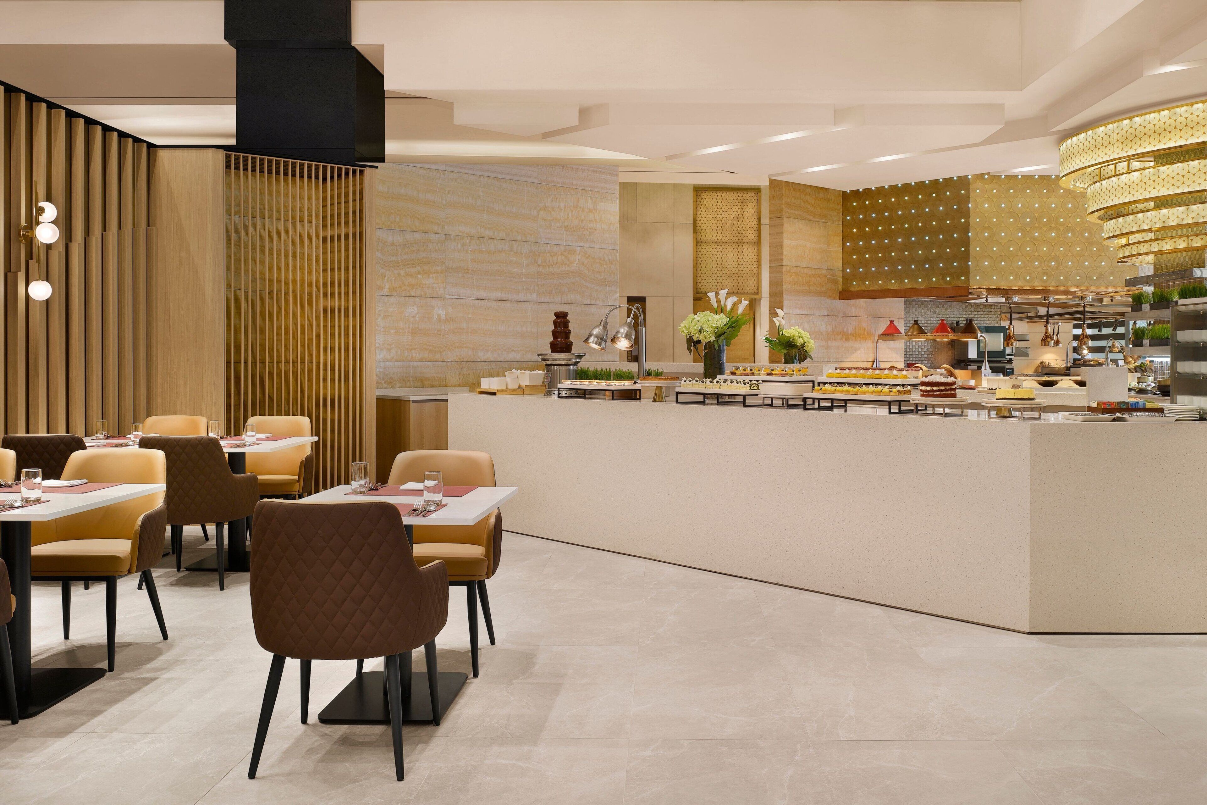 Un restaurante moderno con una zona de bar central, varias mesas y sillas para comer.