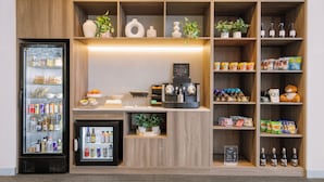 A pantry with shelves stocked with snacks, condiments, and a refrigerator. - Quest Caroline Springs (Caroline Springs)