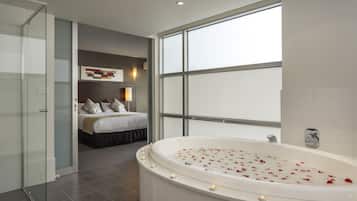 A modern bathroom with a freestanding bathtub, a glass shower enclosure, and a large window providing natural light.