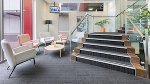 A modern lobby with a staircase, seating area, and a TV screen. - Quest Caroline Springs (Caroline Springs)