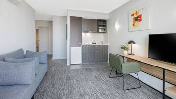 A modern living room with a grey sofa, a wooden dining table, and a TV.