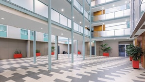A spacious indoor area with a checkered floor pattern, multiple levels with glass railings, and potted plants. - Quest Caroline Springs (Caroline Springs)