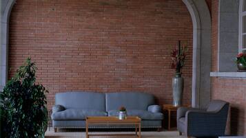 Ein gemütlicher Sitzbereich mit Ziegelwand, grauem Sofa, Holztisch und einem Topfpflanzen.