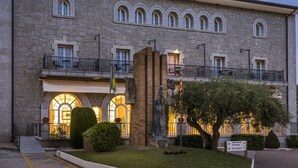 Un edificio de piedra con ventanas arqueadas, una estatua y un letrero que indica un restaurante y bar.