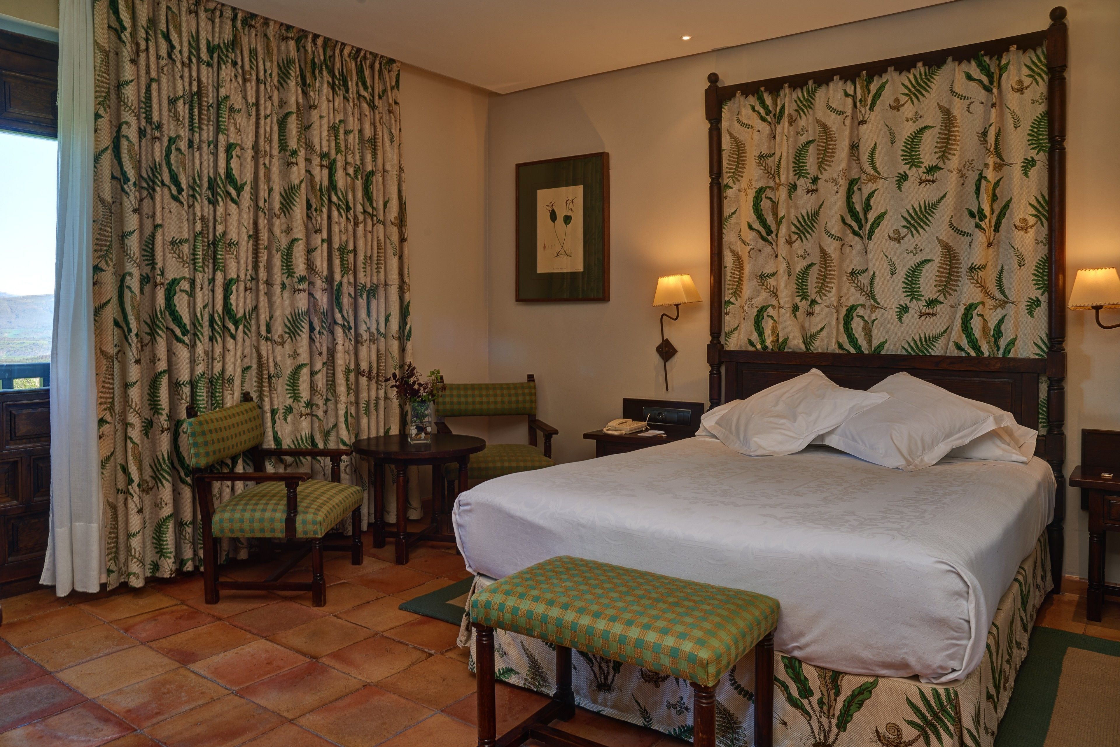 Une chambre d’hôtel avec un grand lit, une banquette, une petite table et une chaise.